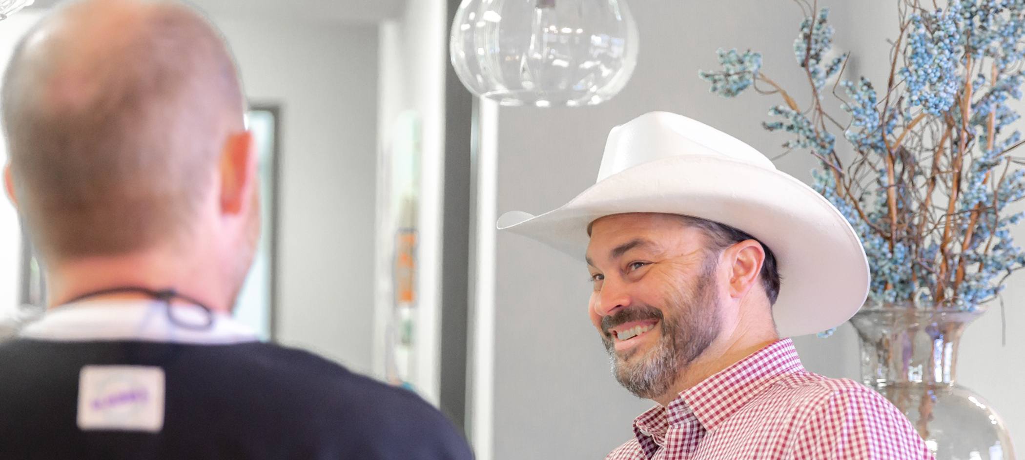 Man in white cowboy hat smiling at dentist