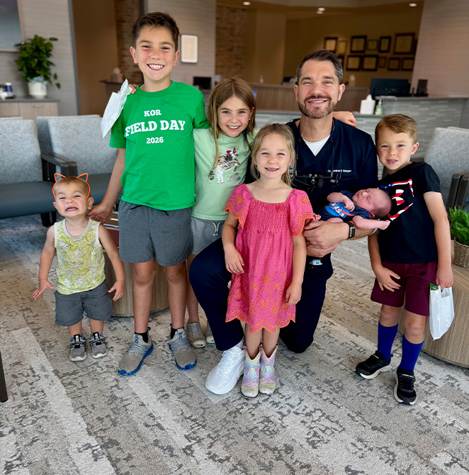 Doctor Naeger smiling with several kids in the dental office