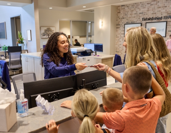 Person handing a card to a dental office receptionist