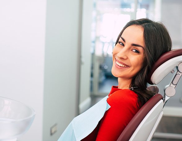 Female patient in dental chair smiling after teeth whitening in College Station