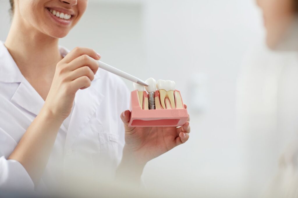 A dentist showing a patient a model of a dental implant.